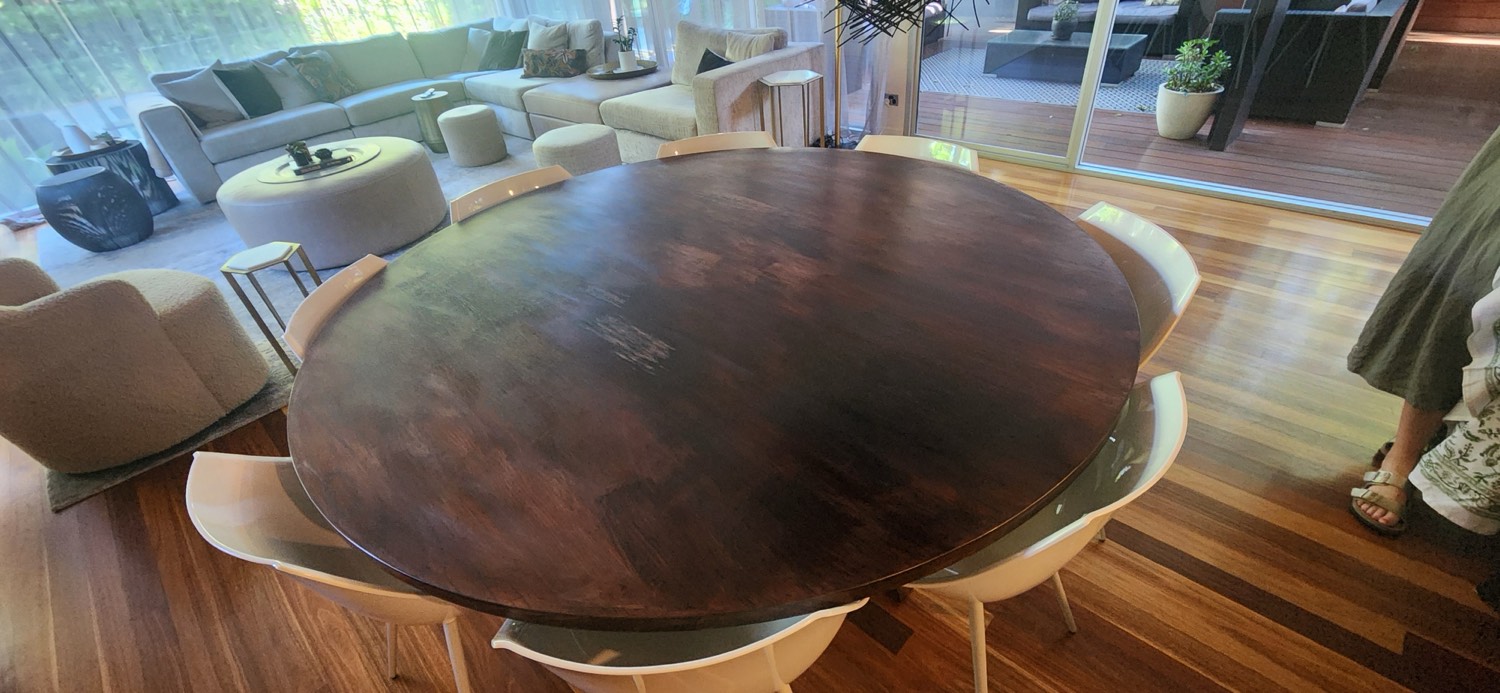 Large round solid oak dining table in an Eaglemont home before restoration, surface blotchy and clouded with damage